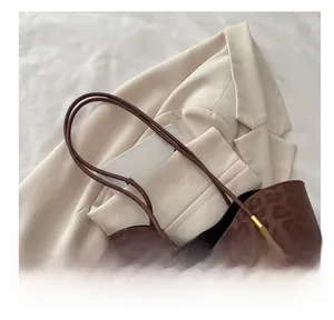 Detail of thin double straps and gold metal hardware on leopard print tote bag