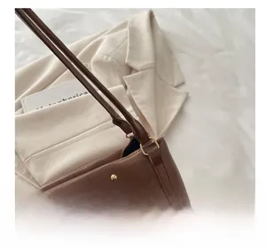 Close-up of vintage brown leather tote bag with unique cut-out handle and gold metal studs