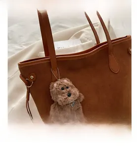 Dettaglio della grande borsa tote in pelle scamosciata caramello con ciondolo peluche
