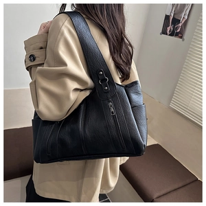 Detail of black pebbled leather tote bag with dual front zippers and wide shoulder strap