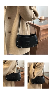 Detail of black underarm bag featuring heart-shaped stitching and silver metal rivets