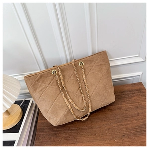 Macro detail of brown quilted suede tote bag with elegant gold chain shoulder strap