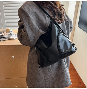 Détail d'un grand sac cabas noir avec fermeture argentée dans un décor de bureau