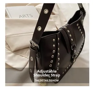 Detail of adjustable strap with silver rivets on dark brown leather saddle bag