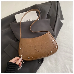 Brown crocodile-pattern crescent bag with heart patch and silver rivets on suit background