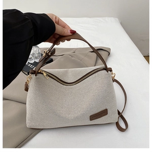 Detailed close-up of retro canvas tote bag with brown leather trim and metal zipper closure