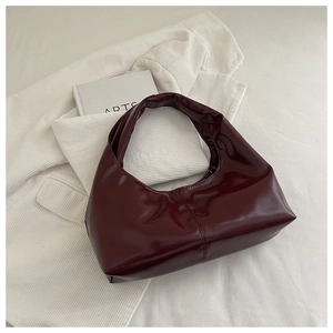 Detail of burgundy glossy hobo bag on white corduroy with high-shine mirror finish