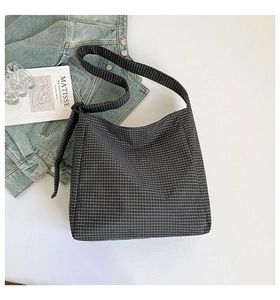 Vue détaillée du sac en toile à carreaux stylisé avec livres et veste en jean