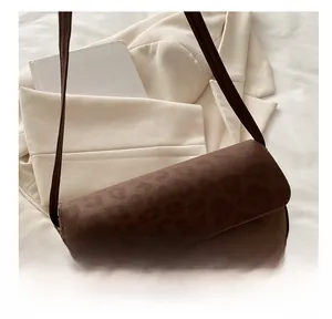 Detail of leopard print faux suede shoulder bag with gold hardware on a beige blazer