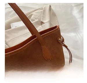 Dettaglio della borsa tote in pelle scamosciata marrone con cuciture e rivetti metallici