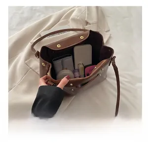 Detail view showing large interior capacity of brown rivet bag with daily essentials