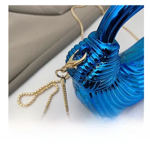 Close-up of bright blue acrylic evening bag with gold chain strap and wavy texture