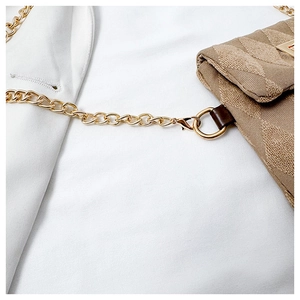 Dettaglio della catena dorata e del tessuto jacquard beige sulla borsa a tracolla alla moda