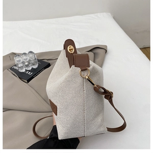 Detail of canvas bucket bag with brown leather trim and golden twist lock closure