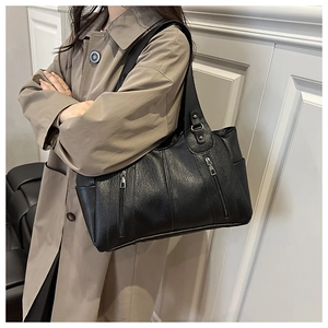Detail of vintage black leather tote bag featuring two decorative vertical zippers and side pocket