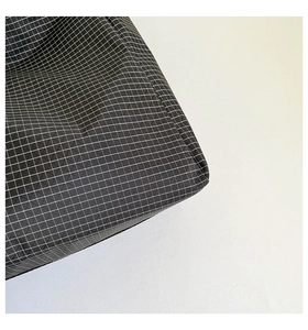 Vue macro d'un tissu ripstop noir avec motif quadrillé blanc montrant les détails de texture