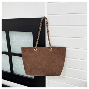 Detail of dark brown suede tote bag with quilted diamond pattern and chain shoulder strap