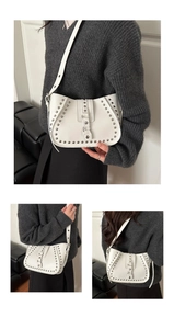 Detail shots of a white crescent shoulder bag with silver rivets and glossy leather finish