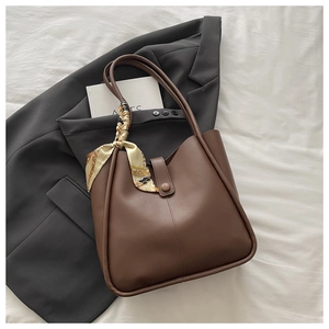 Detail of a deep brown tote bag with decorative silk scarf on a grey blazer