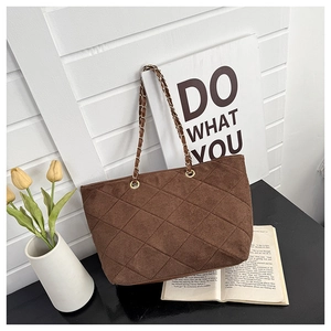 Detail of brown quilted tote bag featuring metal chain strap and retro textures