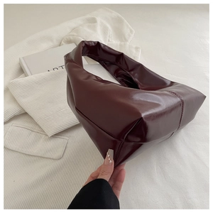 Macro view of burgundy patent leather bag with detailed stitching and soft glossy texture