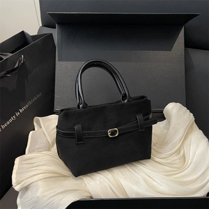 Matte black bucket bag with gold buckle hardware on an elegant white silk background