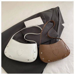 Detail of crescent shoulder bags in white and brown with crocodile pattern and heart studs