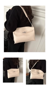 Detailed view of beige leather underarm bag with silver buckle worn by a model