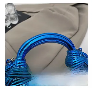 Detail of blue acrylic bag with spiral texture and golden chain links