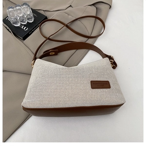Detail of the woven texture and brown leather trim on a stylish crossbody bag