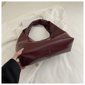 Detail of burgundy patent leather hobo bag with glossy finish and soft texture