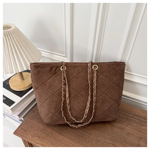 Detail of dark brown quilted suede tote bag with woven gold chain strap and stitching