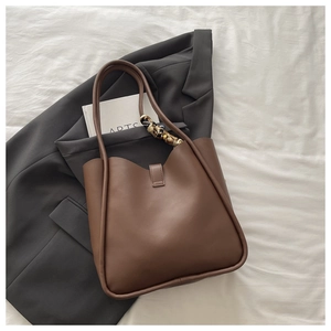 Detail of dark brown leather tote bag with silk scarf on a grey suit jacket
