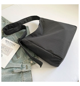 Vue à plat d'un sac bandoulière en toile à carreaux noir et blanc avec sangle assortie