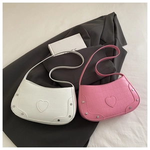 Detail of crocodile embossed half moon bag with heart patch and silver rivets