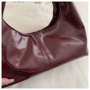 Macro detail of glossy dark red leather handbag with elegant vertical stitching