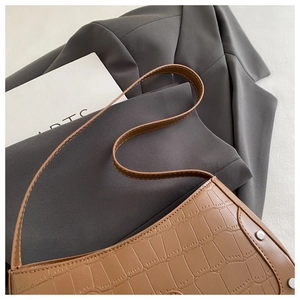 Detailed close-up of brown croco-embossed texture and rivet accents on a baguette bag