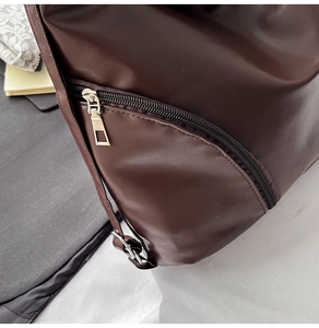 Détail d'un sac à main en cuir marron foncé montrant la poche latérale et la fermeture éclair