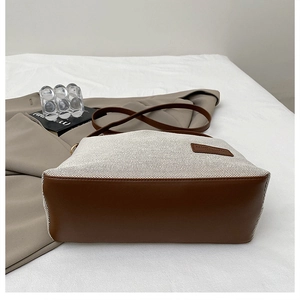 Detailed close-up of canvas tote bag with brown leather accents and logo patch