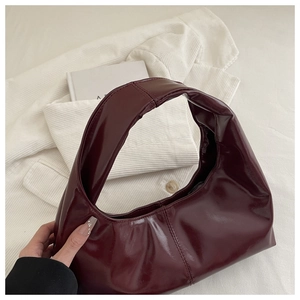 Detail of burgundy waxed leather handbag with soft pleated texture and wide shoulder strap