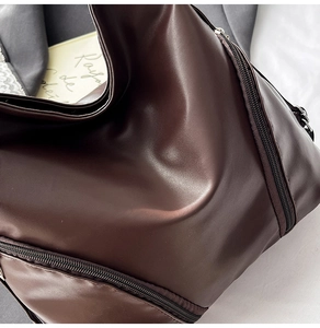 Détail du sac cabas en cuir marron foncé avec plis texturés et fermeture éclair en métal