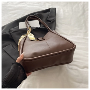 Detail view of large brown faux leather tote bag with decorative yellow floral scarf