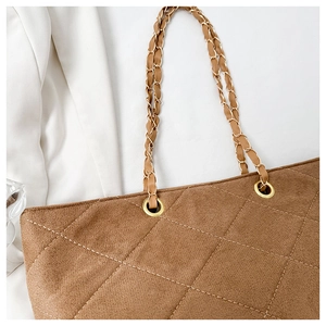 Close-up of brown quilted suede tote bag featuring a gold chain and leather strap