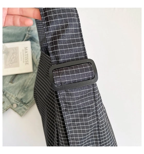 Détail de la boucle de bandoulière noire réglable sur le sac à carreaux noir et blanc