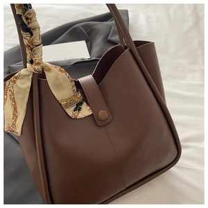Close-up of deep brown tote bag with matte texture, vertical stitching, and floral scarf detail