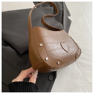 Detailed view of warm brown faux crocodile leather bag with heart patch and silver rivets