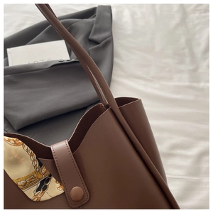 Detailed view of dark brown tote bag with magnetic closure and floral silk scarf accessory