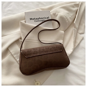 Detailed close-up of dark brown suede shoulder bag on minimalist aesthetic background