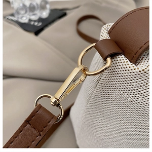Macro shot of golden metal hardware and brown leather strap on a woven crossbody bag