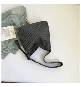 Détail du sac bandoulière en toile à carreaux à côté d'une veste en jean